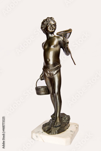 Vintage bronze figurine depicting a boy in swimwear on a rock with a crab net fishnet and basket isolated on white.