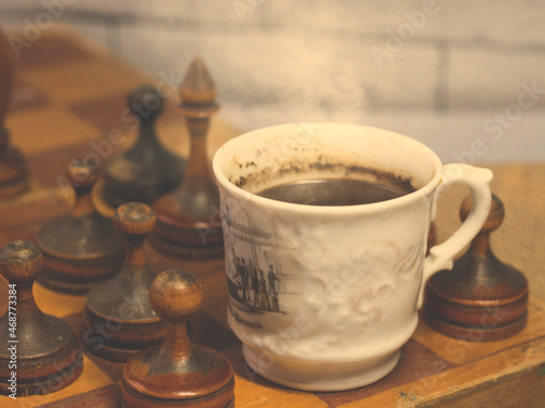 A cup of coffee and an old wooden chess set