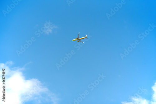 yellow passenger plane under clouds in a blue sky - Travel by air