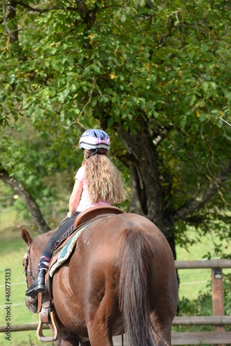 Sicherheit im Reitsport. Kleines Mädchen mit Reithelm auf einem Pferd © Grubärin