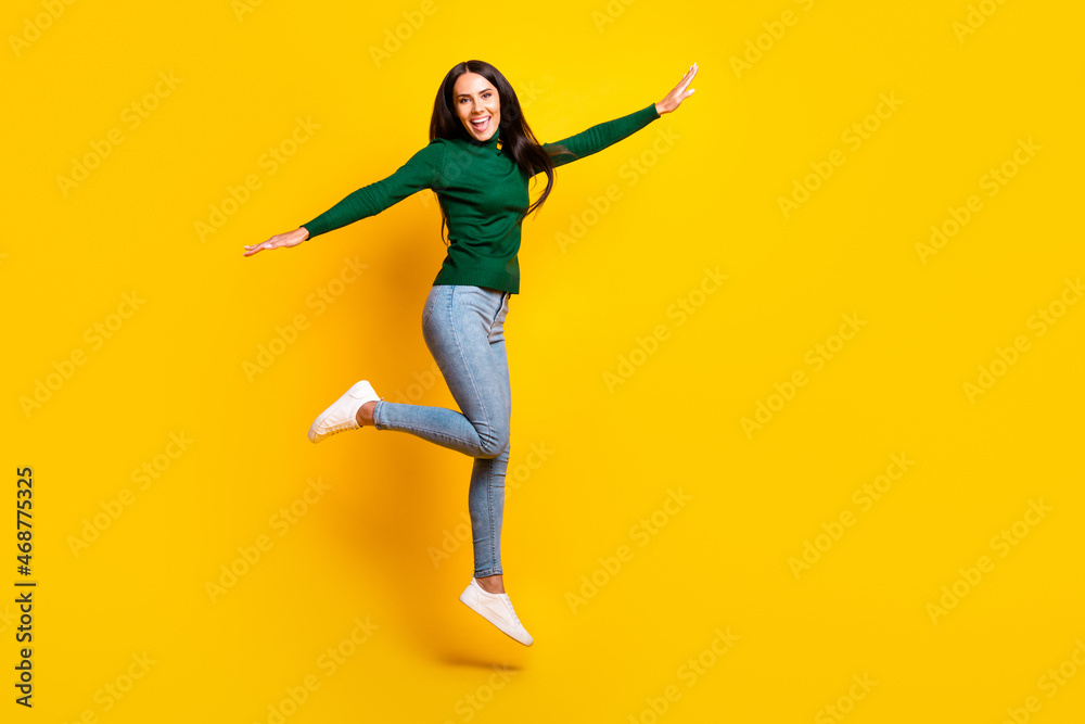 Full size profile photo of nice optimistic brunette lady jump wear green sweater jeans sneakers isolated on bright yellow color background