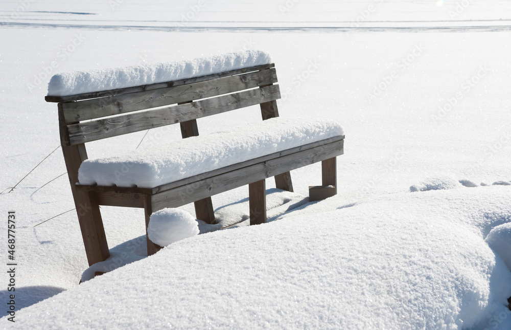 Wooden pier and bench covered with snow