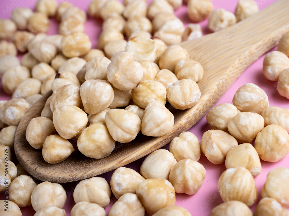 Hazelnuts on a wooden spoon and a pink background. Hazelnuts on a wooden spoon and a pink background.