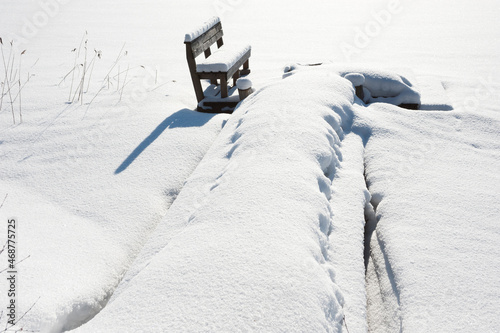 Wooden pier and bench covered with snow