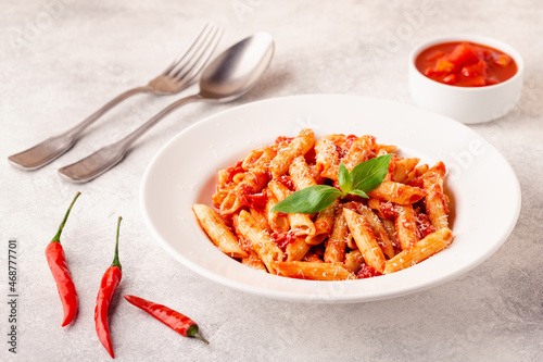 Classic italian pasta penne alla arrabiata with fresh basil on a light background photo