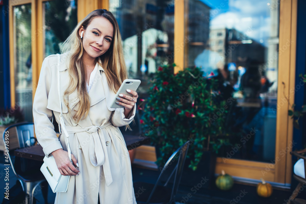Fototapeta premium Happy woman using smartphone in cafe looking at camera