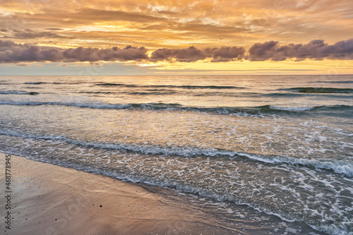 Sunset on Baltic Sea white bright golden orange color and rough sea 