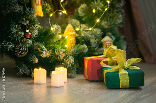 Wrapped gifts are under the tree. Boxes in green and red packages tied with a gold ribbon. Christmas gifts concept photo