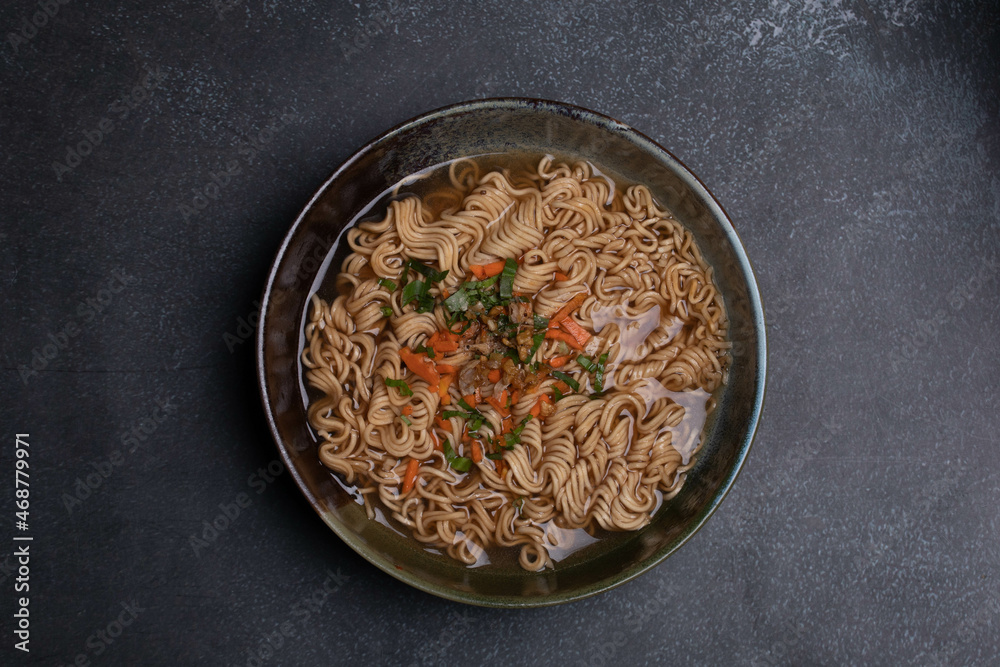 Instant noodles in gray Japanese ceramic lining with black tray, top view. Instant noodles in gray Japanese ceramic lining with black tray, top view.
