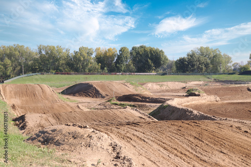 Fototapeta Naklejka Na Ścianę i Meble -  Track for motocross racing competition with breaking bumps under a blue cloudy sky on a sunny day