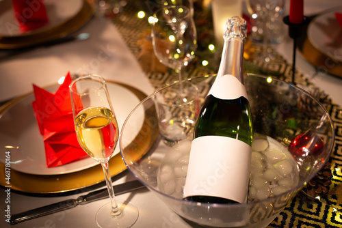 champagne bottle on a christmas holiday festive party table with wine glass on a red and gold shiny decoration