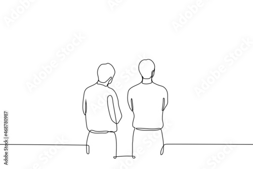 two men are standing with their arms crossed and looking at something above eye level - one line drawing vector. concept of exhibition visitors, passers-by stopped to look, observers or waiting