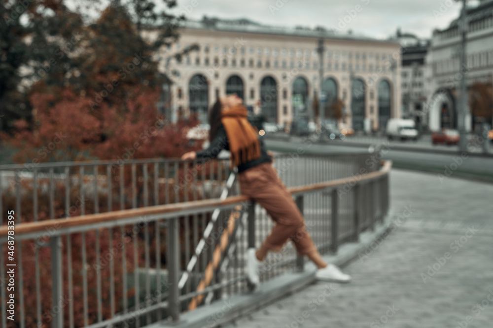 The girl stands at the fence on the bridge in the city. Fun in the city, a walk. The girl stands at the fence on the bridge in the city. Fun in the city, a walk.