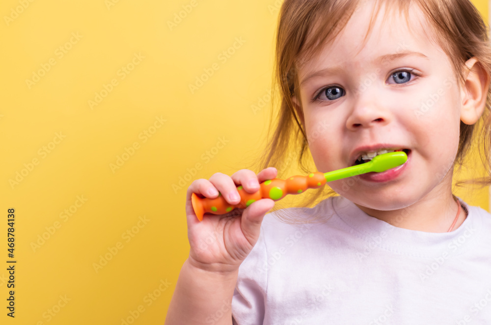 A small child brushes his teeth on a yellow background. A small child brushes his teeth on a yellow background.