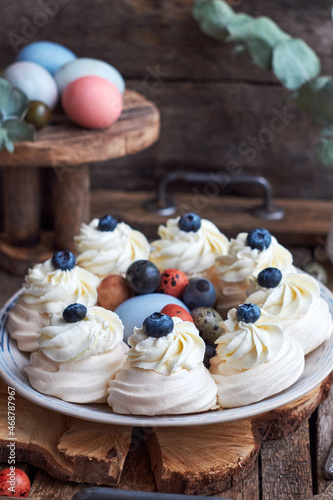 Easter Pavlova cake. Blue, pink eggs, decor, coffee, side view, blueberry.