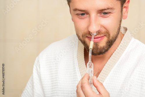 Young caucasian man receiving nasal inhalation Maholda with essential oil in the nose at a hospital photo