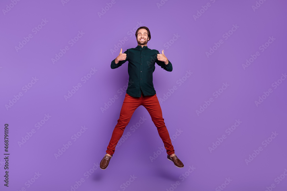 Photo of cute funky young man wear smart casual outfit smiling jumping showing thumbs up isolated purple color background