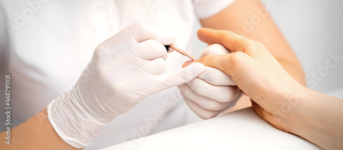 Young woman receiving pink or beige nail polish in a beauty salon