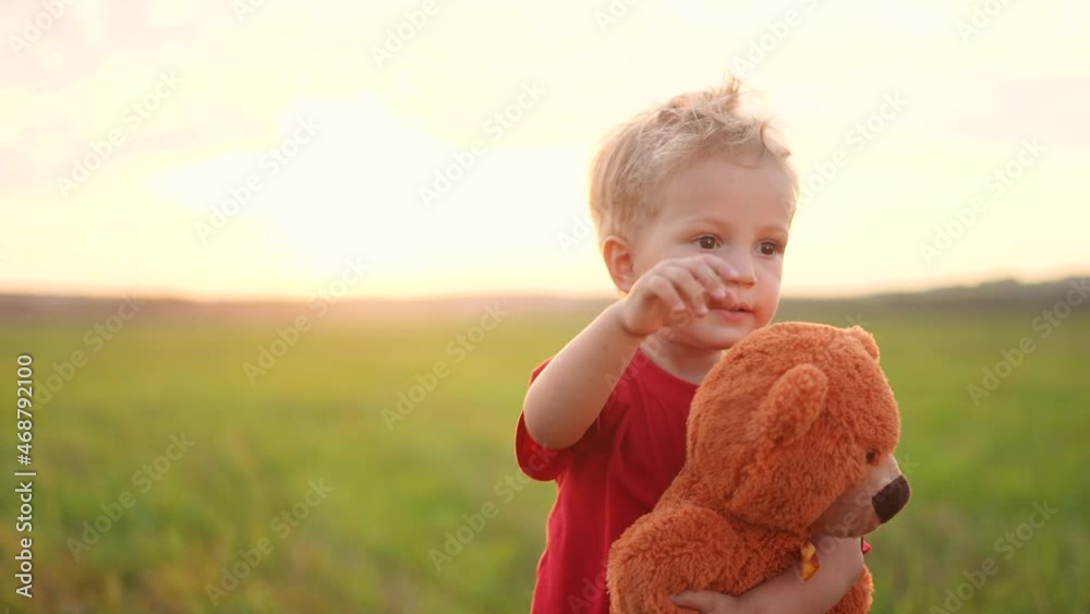 portrait of a baby boy with a toy teddy bear in his hands on nature in ...