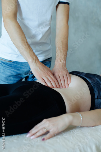 male masseur hands palpate the internal contents of the belly of a young girl