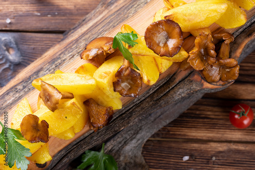 Fried potatoes with chanterelles on wooden board on the table