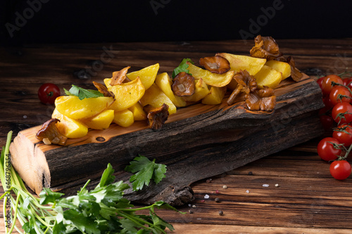 Fried potatoes with chanterelles on wooden board on the table