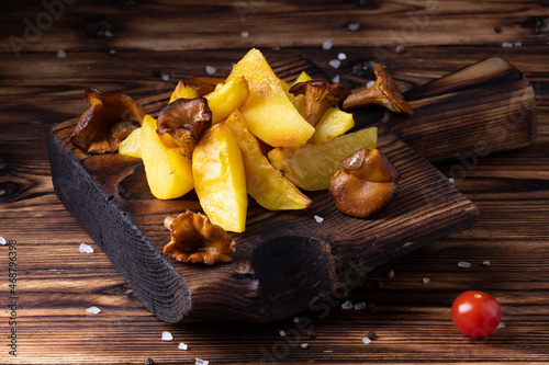 Tasty fried potatoes on cutting board, on wooden table background