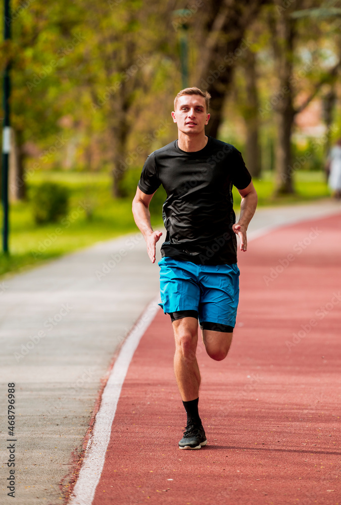 Male athlete running on a road away from camera, full length Male athlete running on a road away from camera, full length