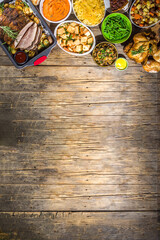 Thanksgiving dinner table with new traditional thanksgiving food - chicken, mashed sweet potatoes, green beans, pecan pie, baked ham pork, mac and cheese, stuffing, modern hard sunny light flatlay