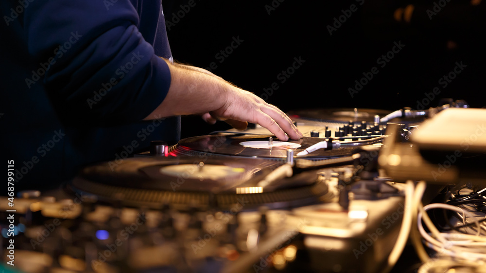 Hip hop dj scratching vinyl records on turntables on party in night club. Professional disc jockey scratches analog disc with music Hip hop dj scratching vinyl records on turntables on party in night club. Professional disc jockey scratches analog disc with music