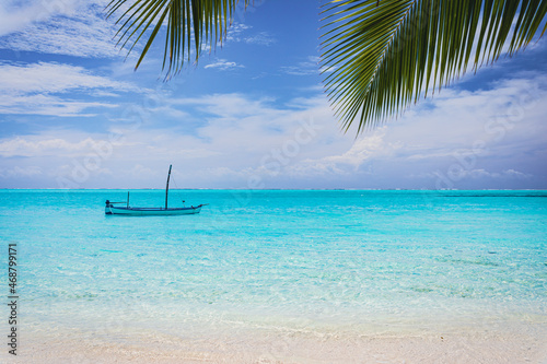 Fototapeta Naklejka Na Ścianę i Meble -  Old fishing boat on a paradise island with turquoise water and palm leaves in the foreground - Maldives