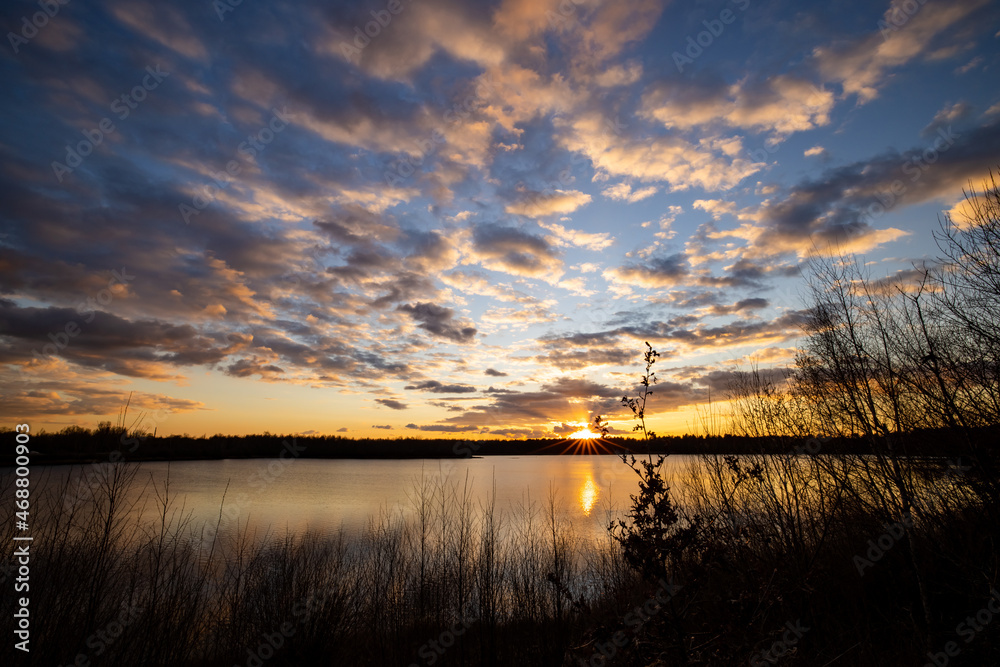 a beautiful blue lake with some tree silhouettes in the foreground under a dramatic sunset sky. High quality photo a beautiful blue lake with some tree silhouettes in the foreground under a dramatic sunset sky. High quality photo