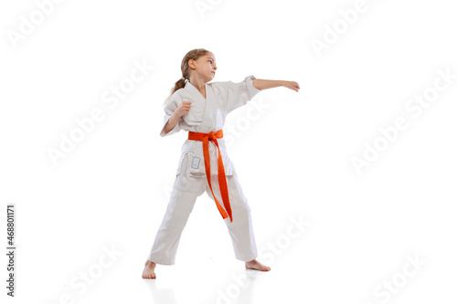 One little girl, young karate in kimono practicing isolated over white background. Concept of sport, education, skills