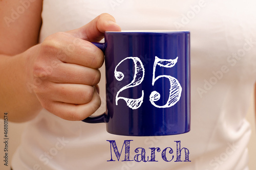 The inscription on the blue cup 25 march. Cup in female hand, business concept