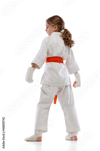 Back view of little girl, young karate posing isolated over white background. Concept of sport, education, skills