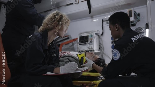 Paramedics riding in ambulance car with patient on stretcher photo