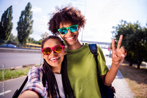 Self-portrait of attractive cheerful carefree couple spending free time sunny day having fun showing v-sign outdoors