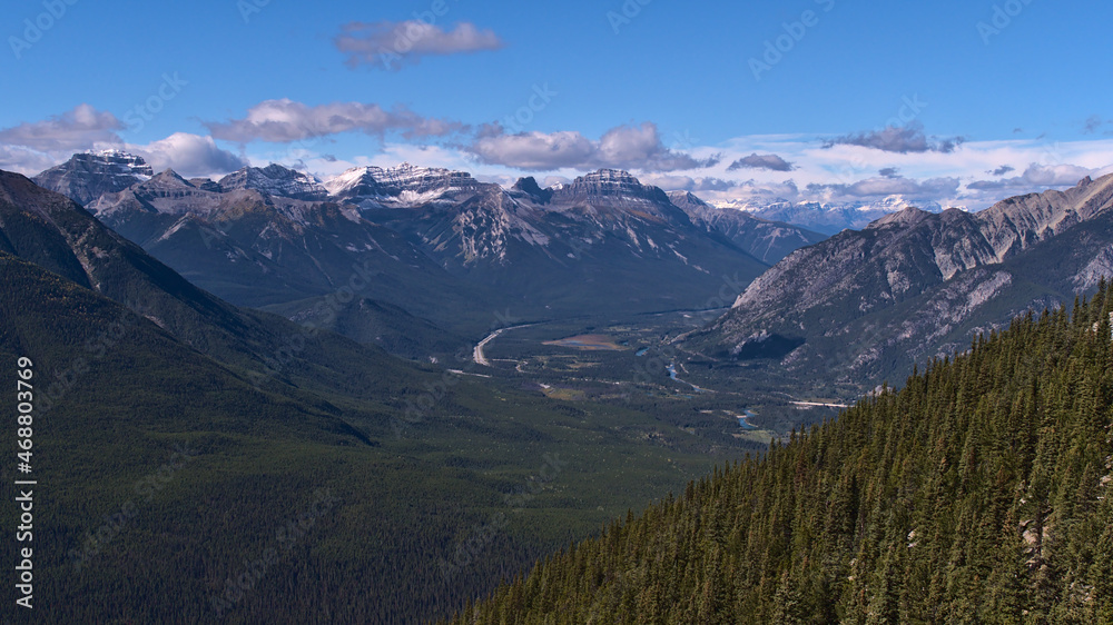 Rugged Rocky Mountains (Massive Range) with snow-capped peaks above Bow Valley with winding river and Trans-Canada Highway near Banff, Canada.
