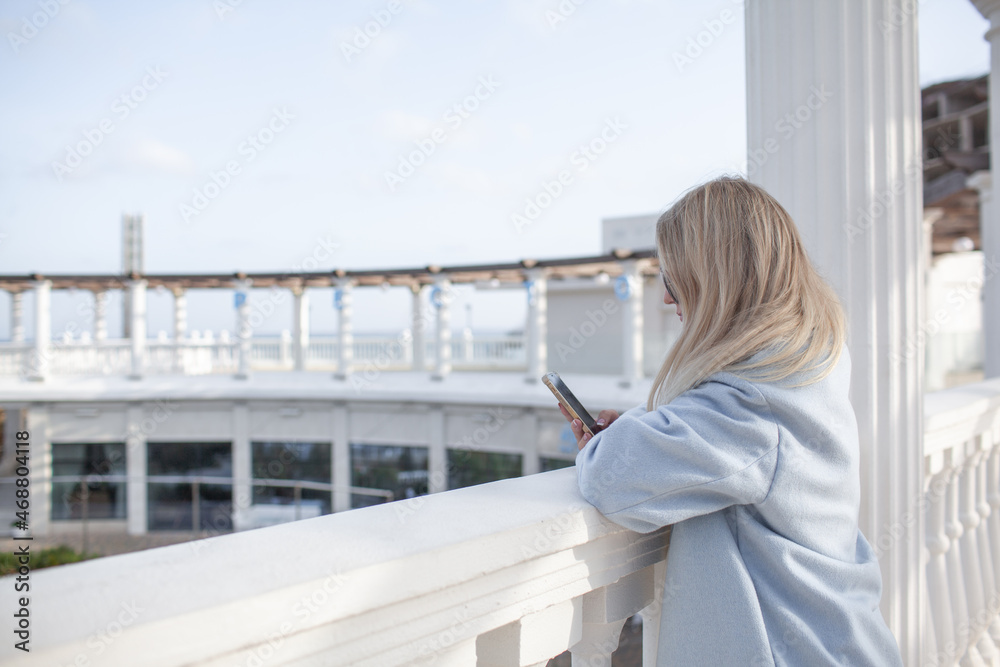 Beautiful woman dressed woolen blue jacket, white scarf and trousers walking in the city, rest on and enjoy the time is in with you Beautiful woman dressed woolen blue jacket, white scarf and trousers walking in the city, rest on and enjoy the time is in with you