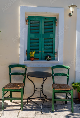 A table with two chairs by the window of a Greek village house.