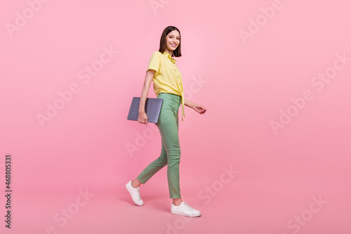 Full body profile side photo of young girl happy positive smile go walk meeting laptop isolated over pink color background © deagreez