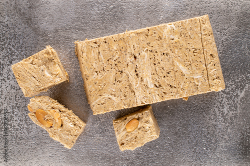 Several pieces of halva with peanuts on a metal tray, close-up, top view.