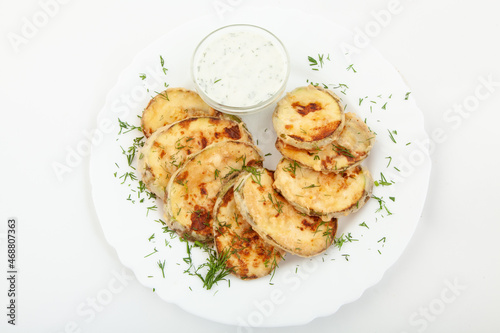 Fried zucchini with sauce in white plate. Top view