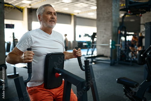 Elderly man in sportswear on exercise machine, gym