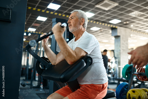 Elderly man, workout on exercise machine in gym