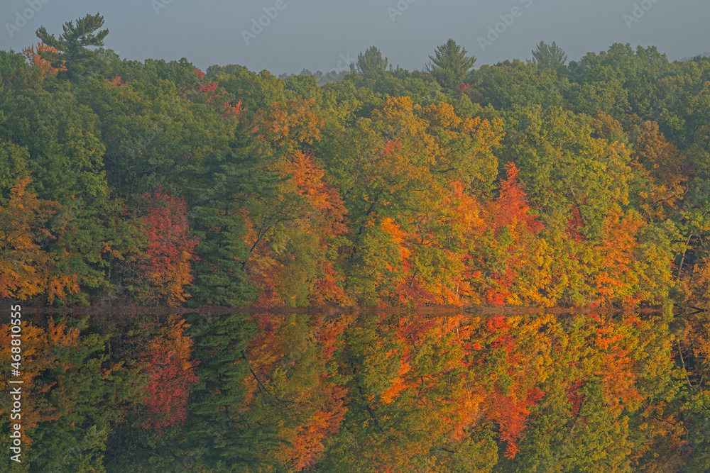 Autumn landscape of the shoreline of Hall Lake with mirrored reflections in calm water, Yankee Springs State Park, Michigan, USA