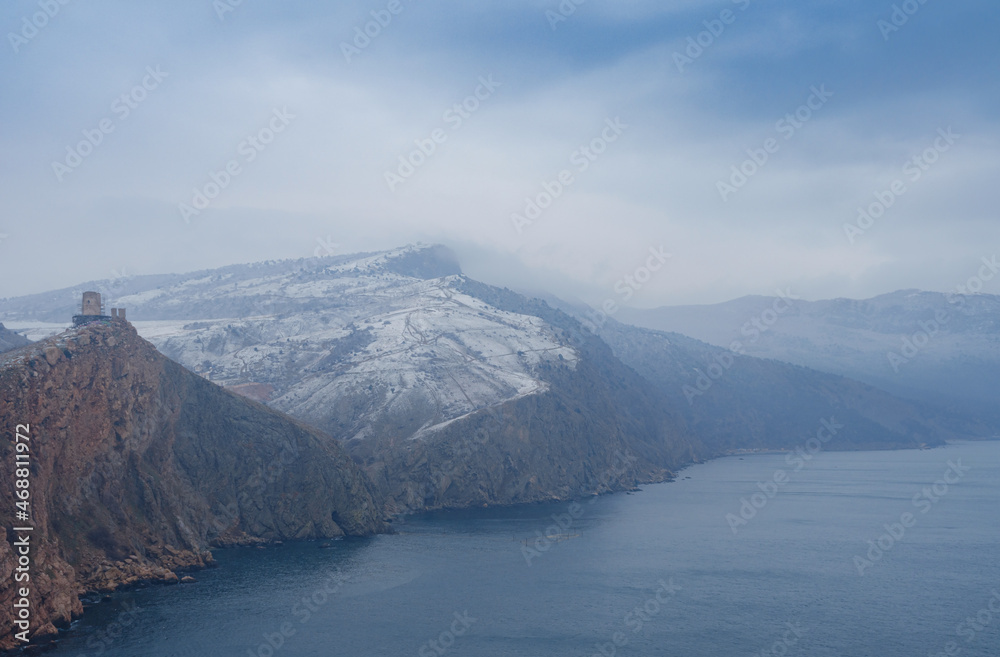 ancient castle ruins on a beautiful rock rise above the sea. winter season, snow is falling. ancient castle ruins on a beautiful rock rise above the sea. winter season, snow is falling.