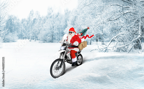 Santa Claus riding a motorbike delivering Christmas or New Year presents, parcels on snow winter landscape.