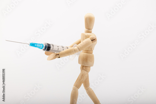 wooden mannequin with syringe against white background