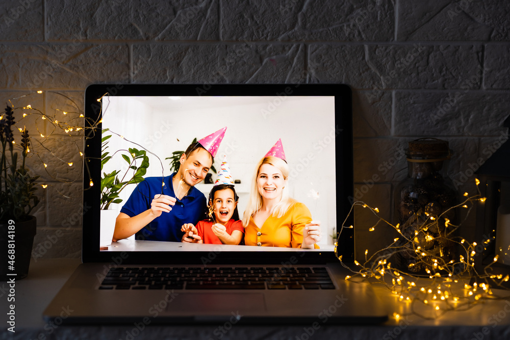 Happy parents hugging cute small kid daughter holding present giving Christmas gift to web camera during virtual family social meeting on video conference call party at home, laptop webcam view. Happy parents hugging cute small kid daughter holding present giving Christmas gift to web camera during virtual family social meeting on video conference call party at home, laptop webcam view.
